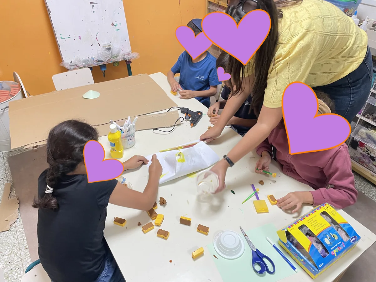ילדים ומחנכת יוצרים עם חומרים שונים בסדנה